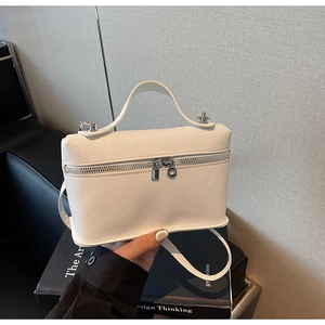 Detailed macro view of white lychee pattern leather and shiny silver zippers on the bag