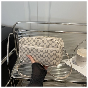 Détail du sac bandoulière avec motif vintage sur une étagère en métal poli