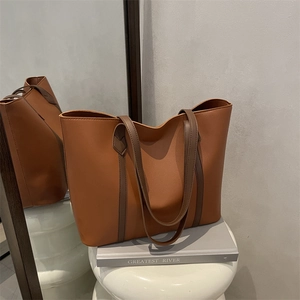 Brown minimalist tote bag for women displayed on books with a creative mirror reflection
