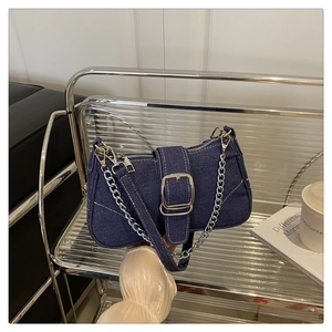 Detailed macro view of denim shoulder bag featuring silver buckle and dual chain strap
