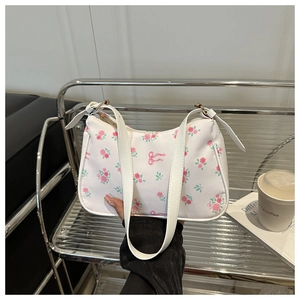 Détail du sac baguette blanc avec imprimés roses et nœuds, design élégant tendance automne 2025