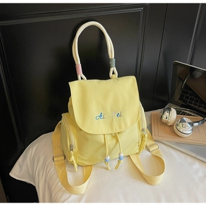 Detail of yellow nylon backpack featuring embroidered logo and colorful beaded drawstrings