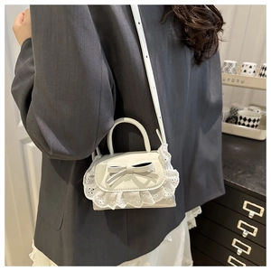 Dettaglio borsa bianca con decorazione a fiocco e raffinati bordi in pizzo traforato
