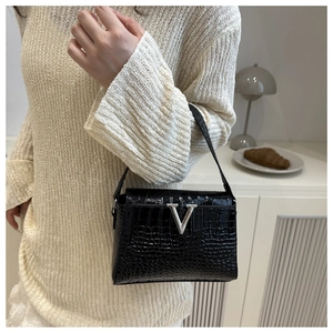 Detail of black crocodile texture handbag with silver V-shaped metal buckle and handle