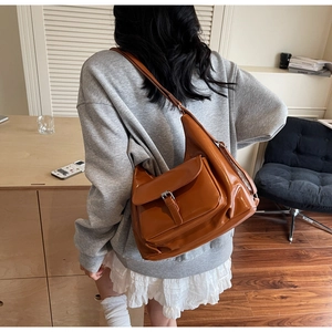 Detailed view of caramel brown shiny leather tote bag with functional buckle pocket