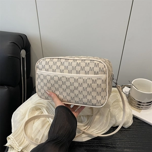 Sac à bandoulière beige chic avec motif M et longue sangle dans un décor élégant