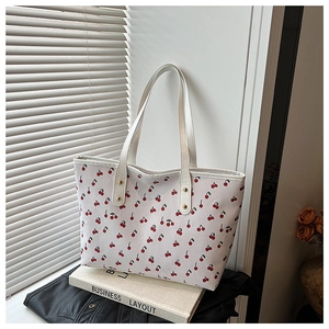 Détail du sac cabas blanc avec imprimés cerises rouges, doubles anses et rivets