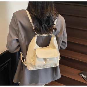 Detail of a chic cream patent leather backpack worn by a model on a wooden staircase