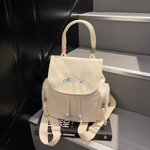 Beiger Nylon-Rucksack mit buntem Griff und Stickerei auf dekorativen Büchern