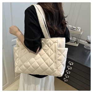 Detail view of the white quilted tote bag with classic diamond stitching and wide strap