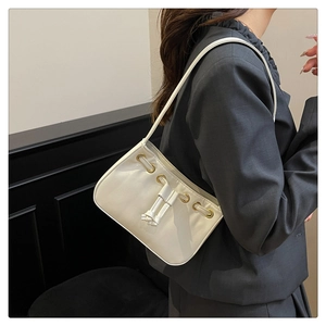 Detail of a creamy white underarm bag featuring drawstring knots and golden eyelets