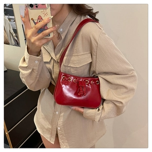 Glossy red faux leather shoulder bag with gold metal eyelets and drawstring detail
