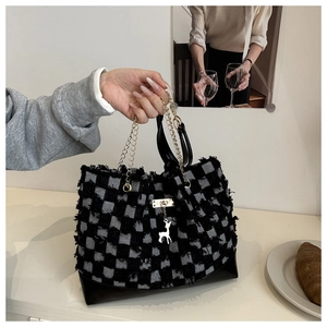 Detail of checkered denim tote with fringe, golden chain handle and silver deer charm