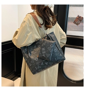 Detail of printed tote bag with mini zipper pouch and stylish chain strap shown on model