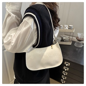 Detail of white moon-shaped shoulder bag with textured faux snakeskin and gold zipper