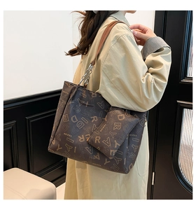 Brown leather tote bag with chain strap and matching coin purse shown on a model