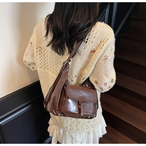 Detail view of a vintage dark brown patent leather tote bag with a glossy mirror finish