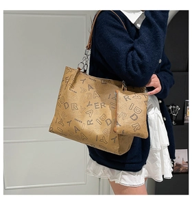 Detail of tan tote bag with letter print and matching mini pouch on a silver chain strap