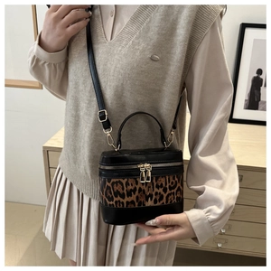 Detailed view of leopard print crossbody bag with dual zippers and leather handle strap