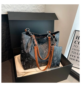 Detail of premium tote bag set with monogram texture and brown leather straps in gift box