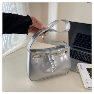 Close-up of metallic silver shoulder bag featuring drawstring closure and gold ring detail
