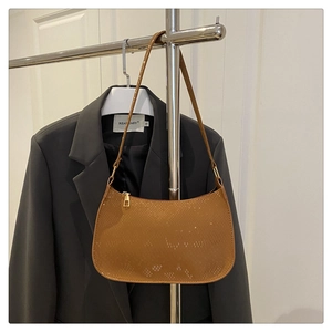 Detail of snakeskin textured brown shoulder bag with golden metal zipper and slim strap