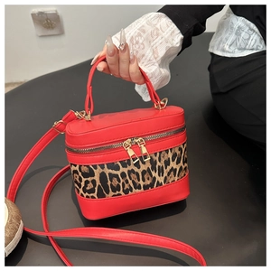 Detail view of red leather box bag featuring leopard print panel and golden zippers