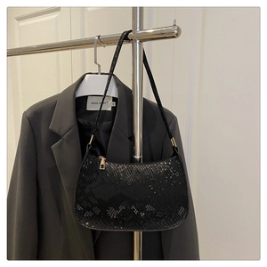 Close-up of black snakeskin pattern underarm bag with gold zipper and smooth texture