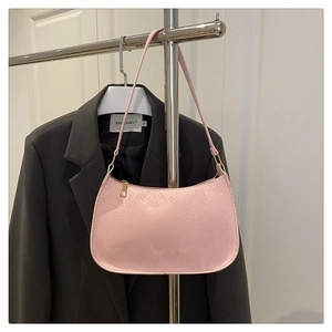 Detailed view of pink snakeskin texture on sleek underarm bag with gold hardware