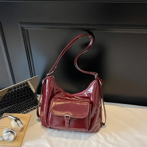 Dark red patent leather tote bag with front pocket shown in a modern office desk setting