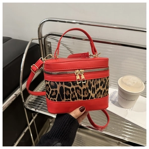 Detail of red leather bucket bag with leopard print panel and gold zippers on a seat