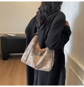 Détail du sac fourre-tout en daim gris-brun avec plaque en métal et poche zippée latérale