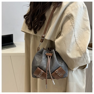 Detail of dark grey bucket bag with brown leather drawstrings and metallic eyelets