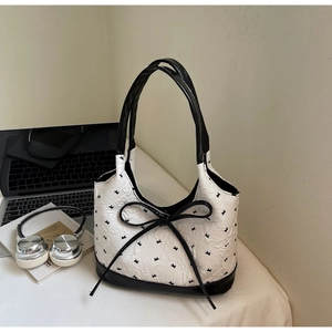 Détail du sac à bandoulière blanc texturé avec nœud noir et motifs brodés d'oiseaux