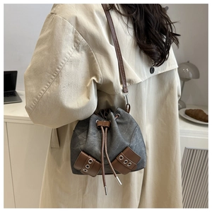 Detail of dark grey canvas bucket bag with brown leather drawstring and metal eyelets