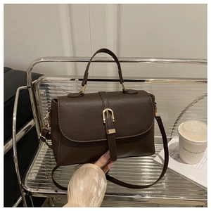Détail du sac en cuir marron foncé grainé avec boucle en fer à cheval dorée élégante
