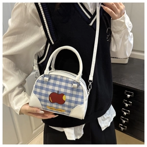 Detail of blue plaid boston bag featuring a red apple pattern and white PU shoulder strap