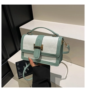 Detail of mint green and white crossbody bag with geometric texture and gold metal buckle