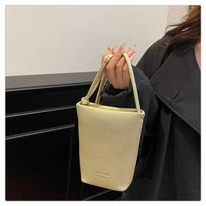 Close-up of litchi grain leather bucket bag in light gold with embossed lettering detail