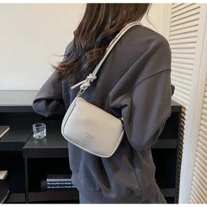 Detail of silver knot-shoulder strap and pebbled texture of this chic underarm bag