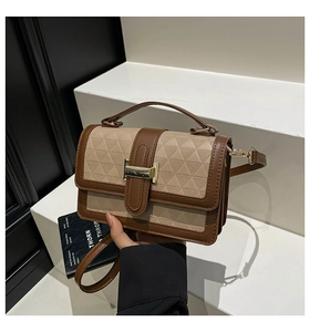 Detail of the embossed geometric texture and gold clasp on the brown leather crossbody bag