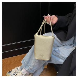 Detail of champagne gold bucket bag in lychee leather showing elegant grain and texture