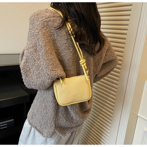 Detail of yellow lychee grain leather mini crossbody bag styled with knit sweater