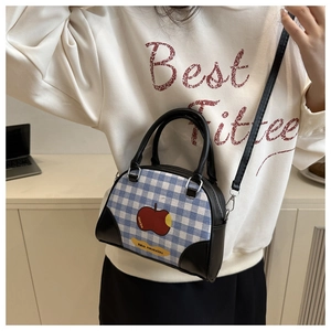 Detail of blue plaid crossbody bag with red apple print and black leather strap