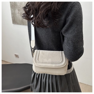Dettaglio borsa a tracolla in pelle scamosciata bianco crema con cuciture a U e tracolla jacquard