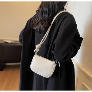 Detail of white litchi pattern leather crossbody bag with knot shoulder strap design