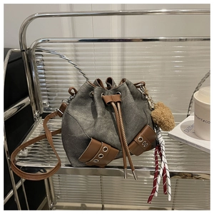 Detail van grijze denim emmertas met bruine lederen trekkoord en hartje accessoires