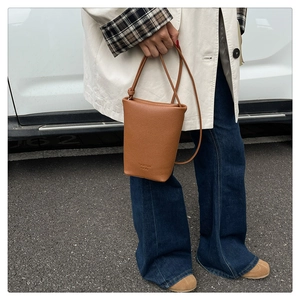 Detailansicht der braunen Leder-Eimertasche mit Litschi-Maserung und Marken-Prägung
