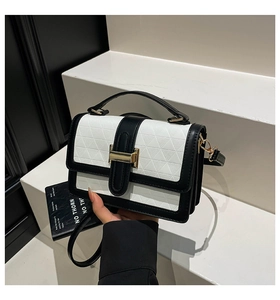 Detail of black and white contrast handbag with geometric triangle embossing and gold buckle