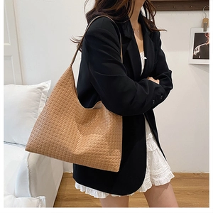 Close-up of woven texture on a brown oversized tote bag worn by a model in a studio